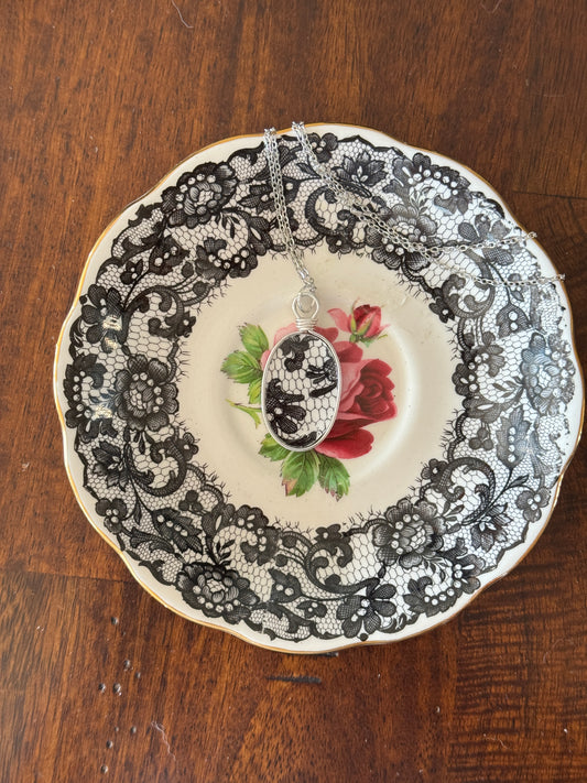 Decorative plate with black lace around a central floral design on a wooden surface