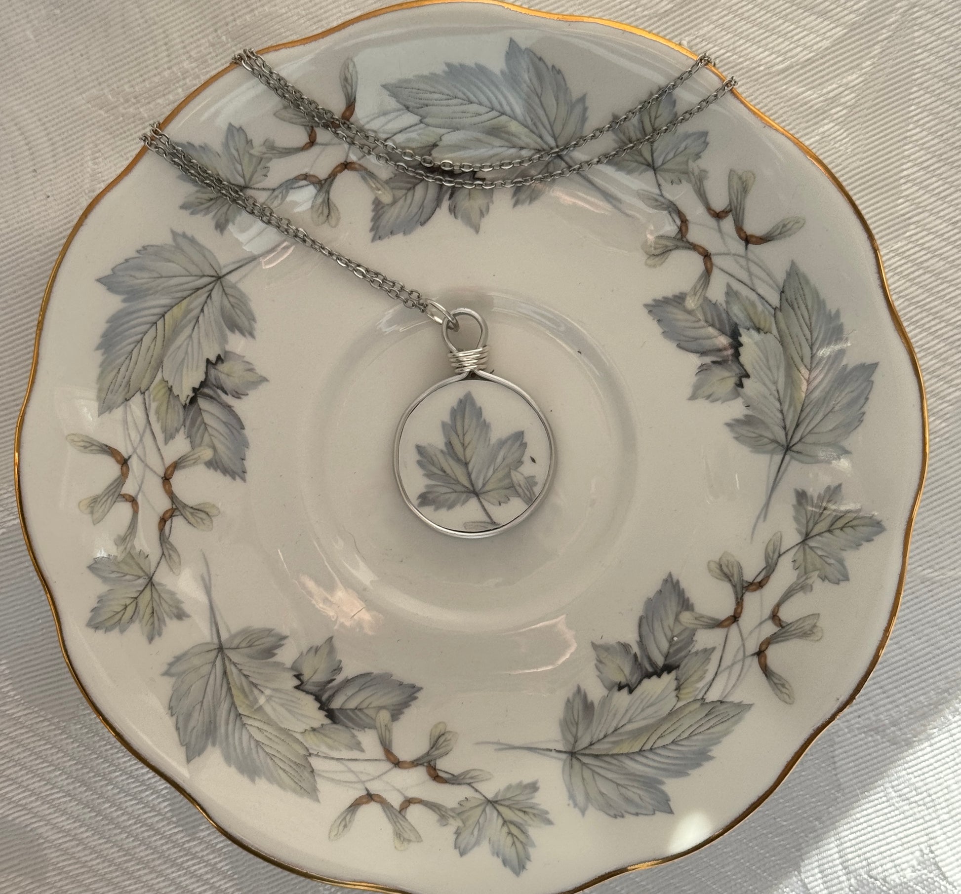 Necklace with a leaf pendant on a decorative plate with leaf patterns