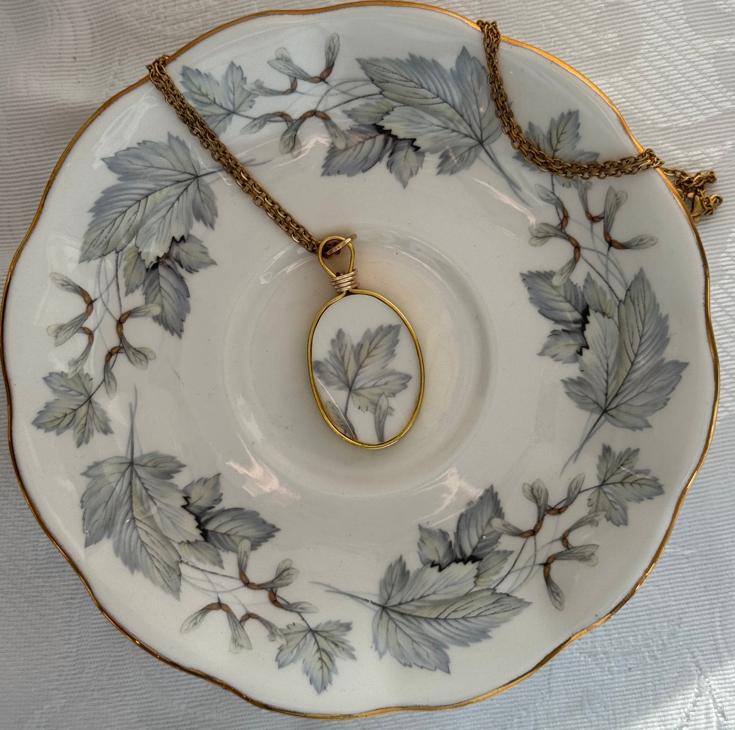 Necklace with pendant on a decorative plate with leaf pattern