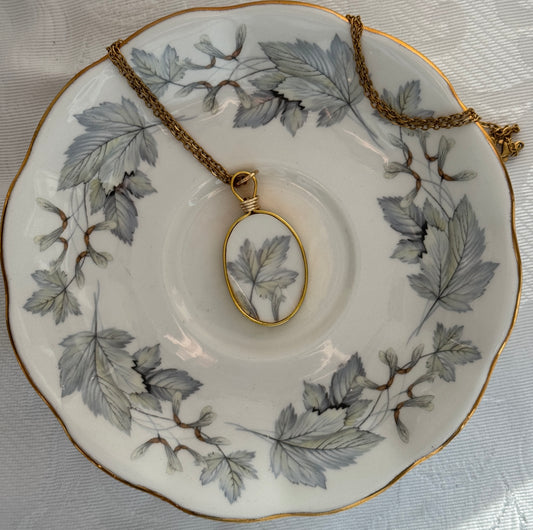 Necklace with pendant on a decorative plate with leaf pattern