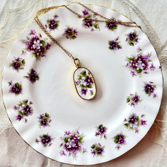 Necklace with a floral pendant on a decorative plate with purple flowers