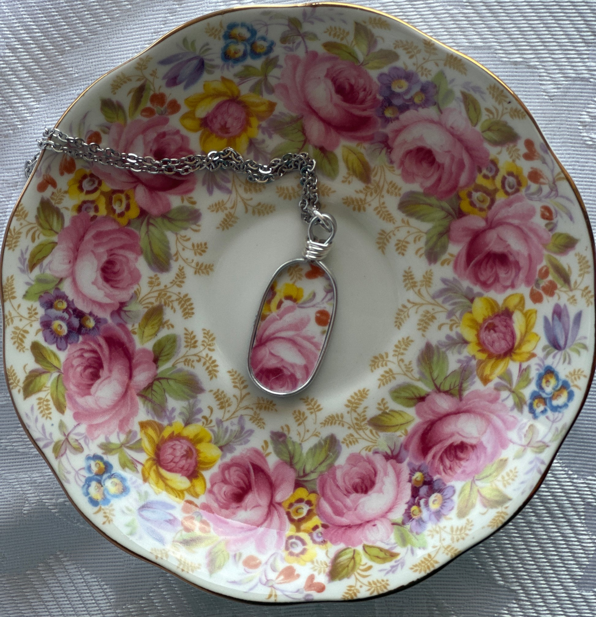 Necklace with a floral pendant on a decorative plate with floral pattern