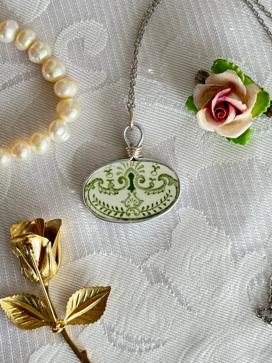 Necklace with a decorative pendant, pearl bracelet, and gold and pink rose on a textured fabric background