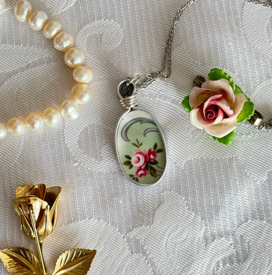 Necklace with floral pendant and rose decorations on a textured fabric background