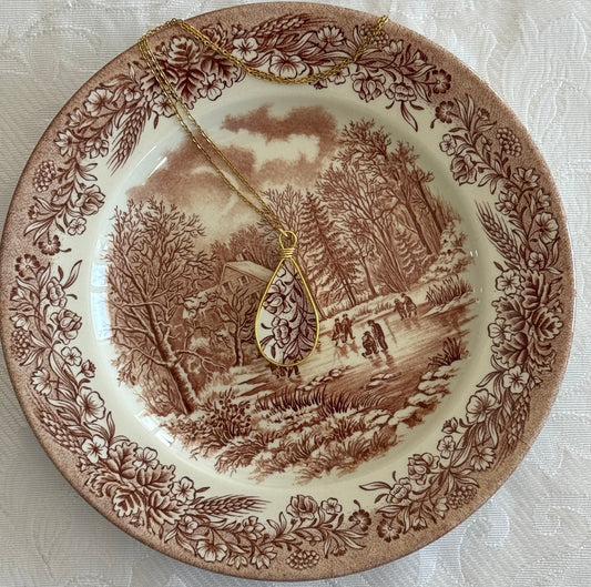 Decorative plate with a landscape design and a gold necklace on top