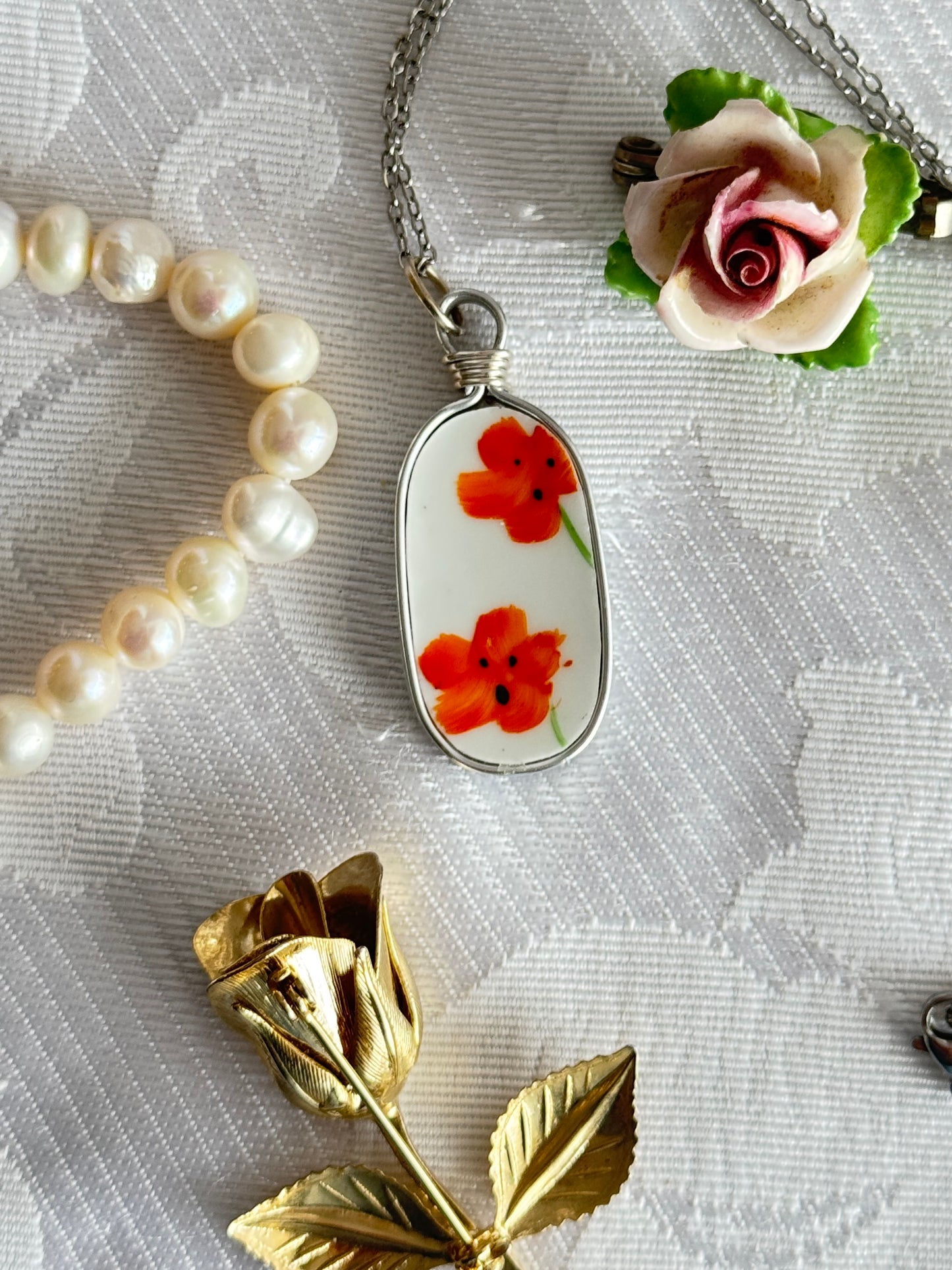 Necklace with floral pendant and pearl beads on a textured surface