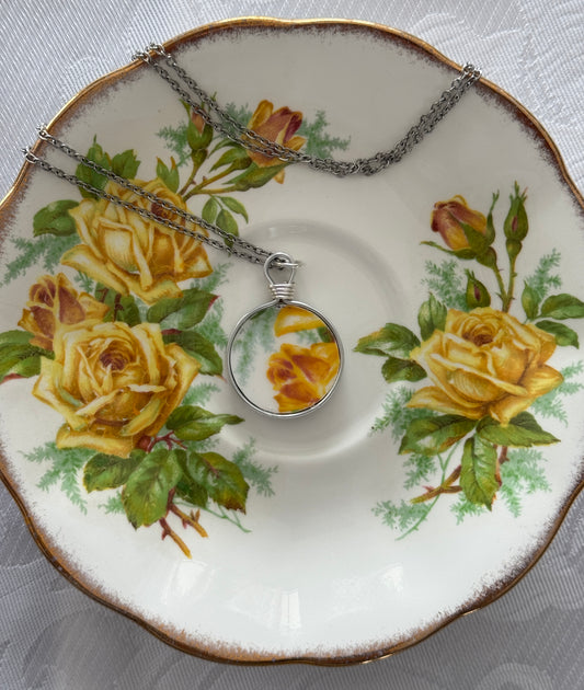 Necklace with pendant on a decorative plate with yellow roses