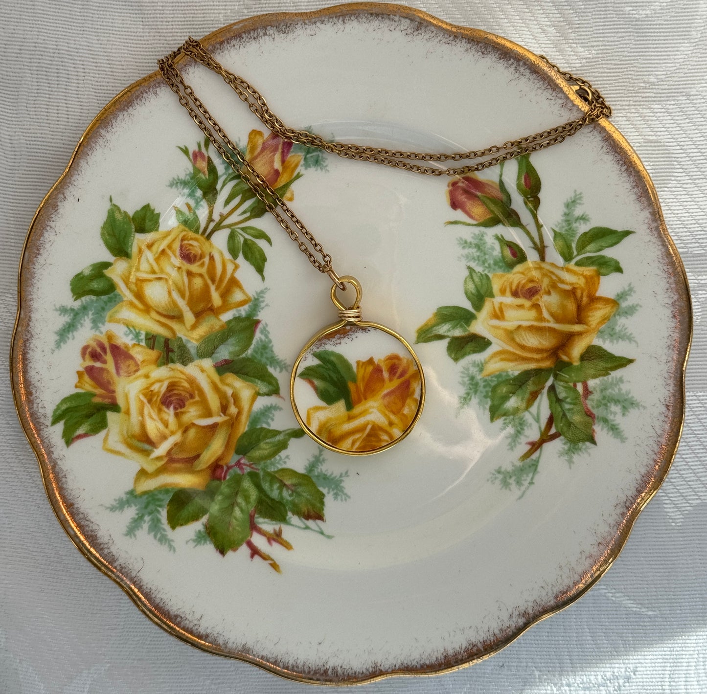 Necklace with a rose pendant on a decorative plate with yellow roses