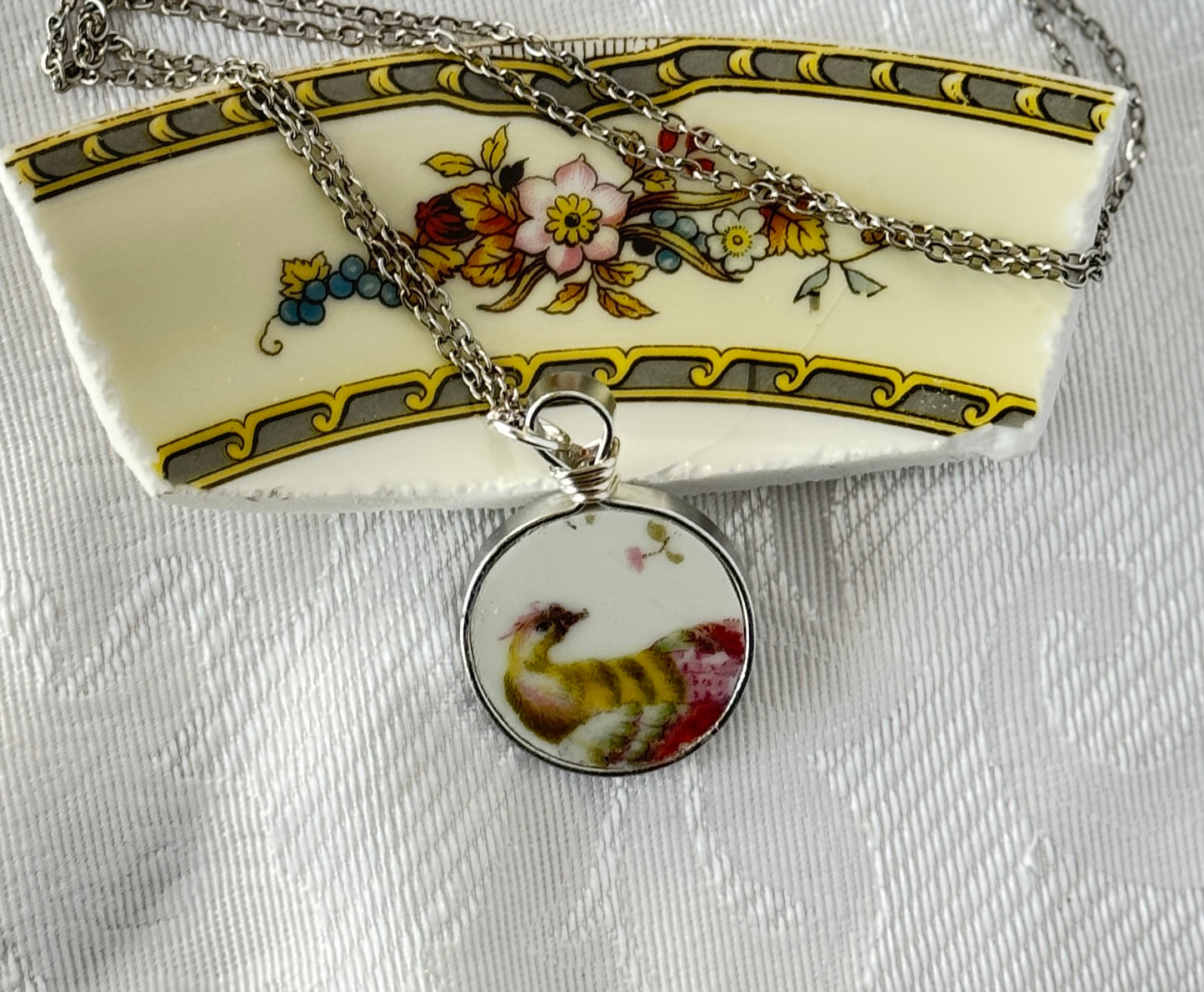 Necklace with a round pendant featuring a rooster design on a decorative plate background.