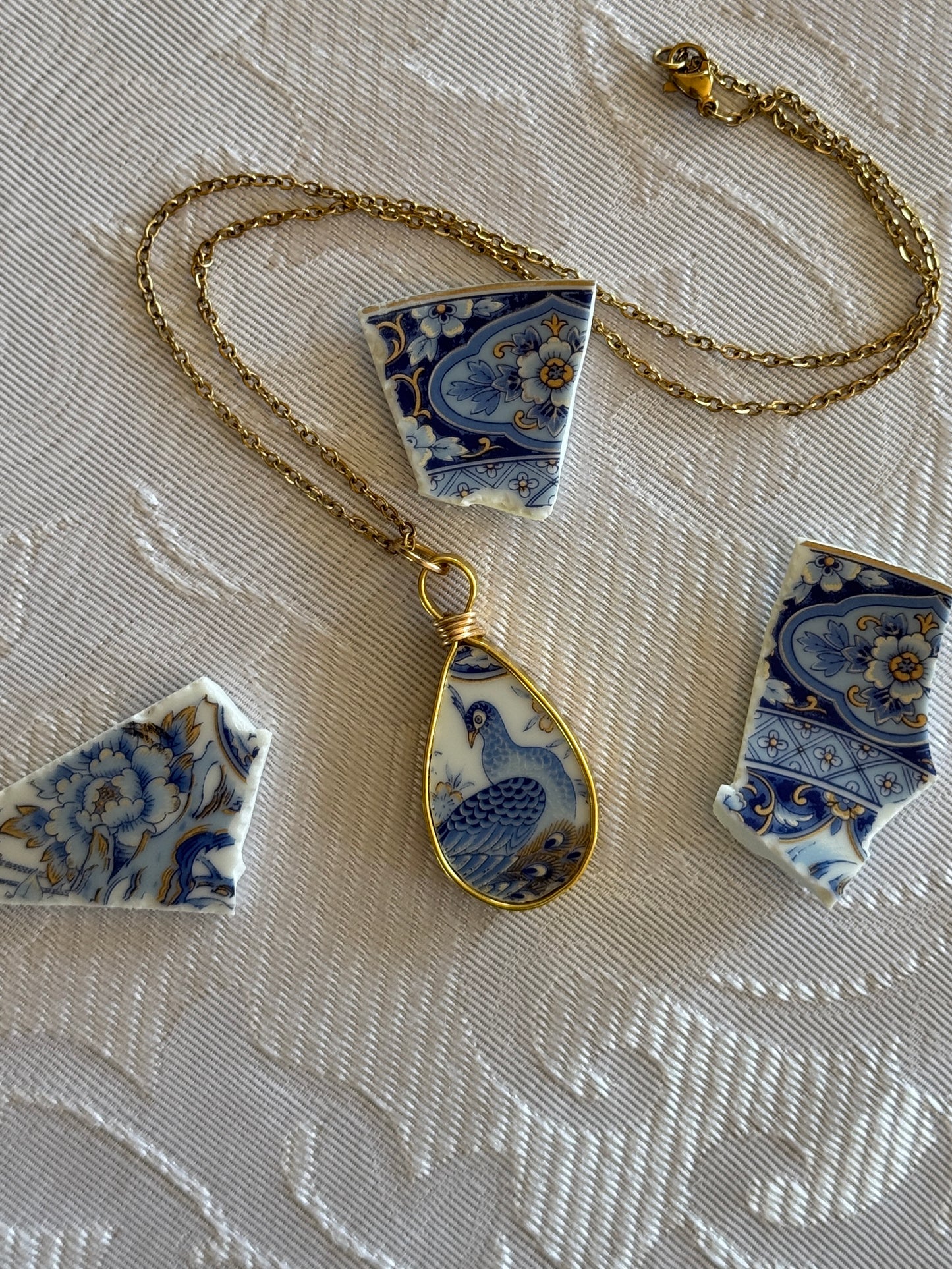 Necklace with a blue and white ceramic pendant on a textured surface