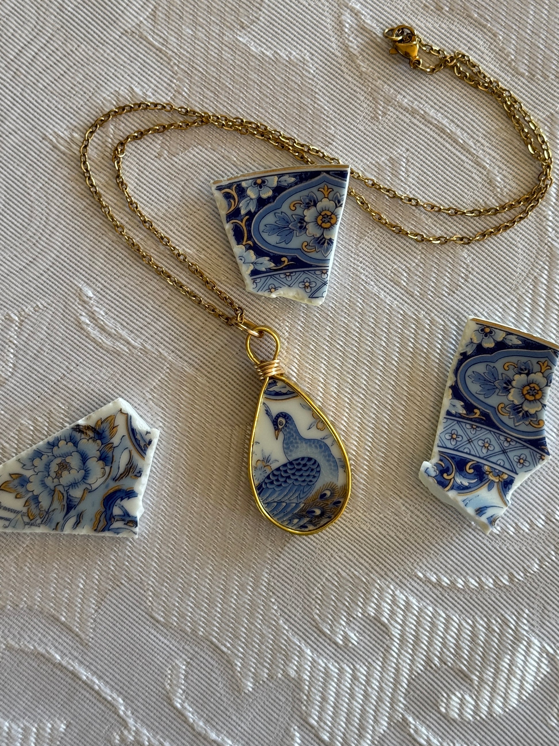 Necklace with a blue and white ceramic pendant on a textured surface