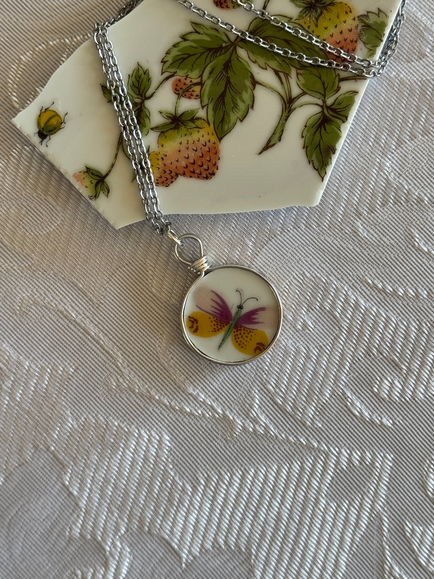 Necklace with a round pendant featuring a butterfly design on a floral-patterned fabric background.