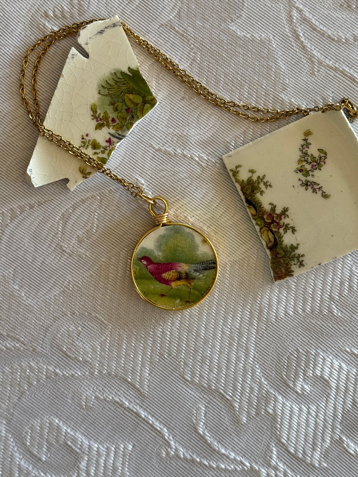 Necklace with a pendant featuring a red bird on a textured surface