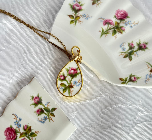 Teardrop-shaped pendant with floral design on a white fabric background