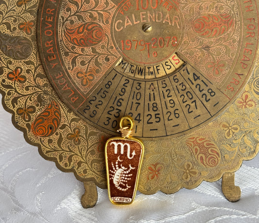 Vintage-style calendar with decorative border and Scorpio pendant on a white background