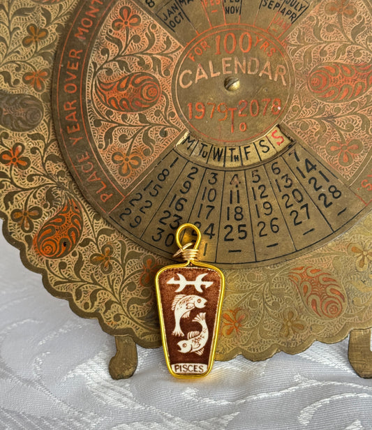 Decorative calendar with pisces zodiac sign pendant on a textured surface